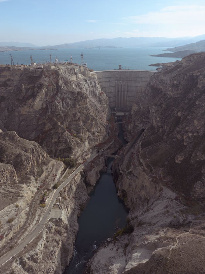 Spectacular birds-eye view of a massive dam and reservoir surrounded by rugged cliffs and nature.