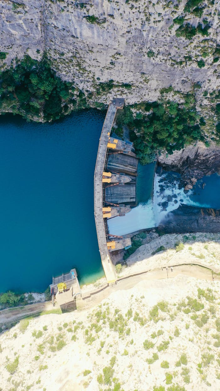 A breathtaking aerial shot of a dam with turquoise waters and lush surroundings, perfect for travel and nature enthusiasts.